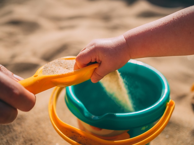 Babymeisje met plezier spelen op een zandstrand met een emmer op een zonnige zomerdag