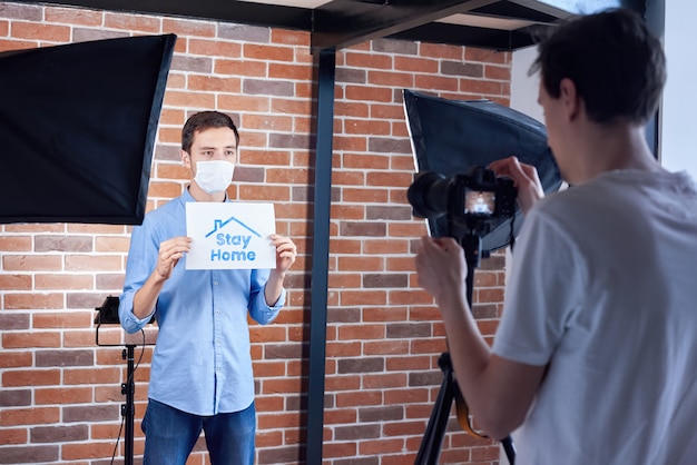 Backstage van de kaukasische mens die aan camera in medisch masker spreekt