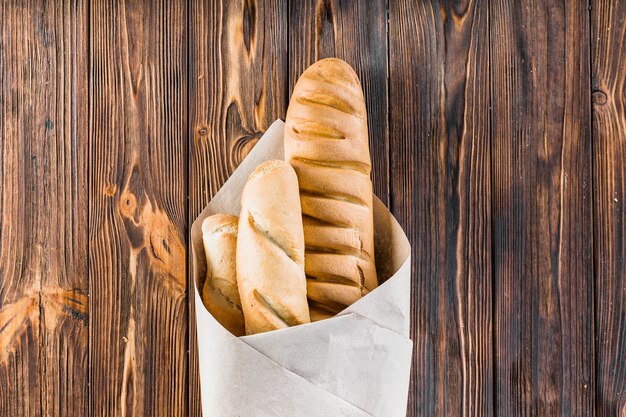 Baguettes gewikkeld in het papier op de houten achtergrond