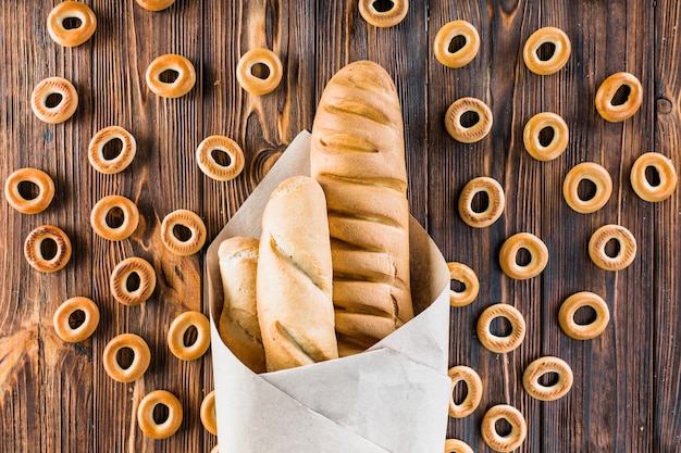 Baguettes gewikkeld in papier omgeven met bagels op houten achtergrond
