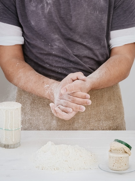 Baker klapt in zijn handen met bloem in de keuken, klaar om te bakken