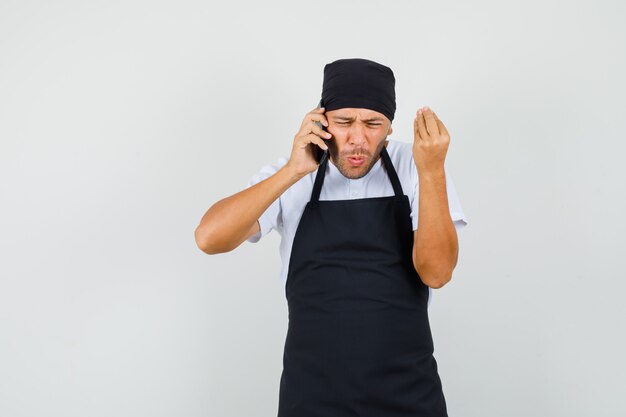 Baker man iets op mobiele telefoon in t-shirt bespreken