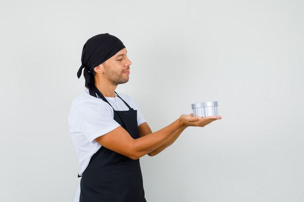 Baker man kijken naar geschenkdoos in zijn handpalmen in t-shirt