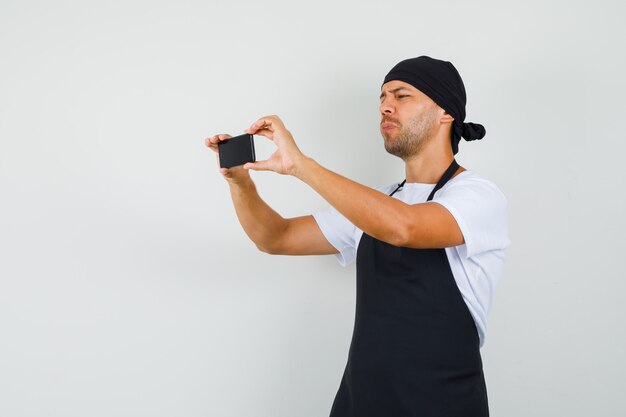Baker man nemen foto op mobiele telefoon in t-shirt