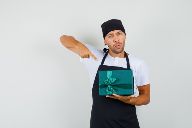 Baker man wijzend op geschenkdoos in t-shirt