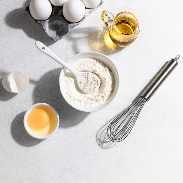 Bakingrediënten meel eieren zwaaien boter en melk op een witte betonnen achtergrond Bakconcept