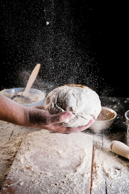 Bakkers die bloem over het kneeddeeg sprenkelen