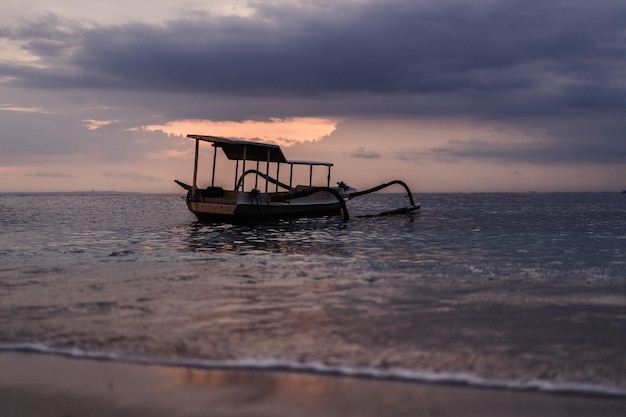 Balinese authentieke vissersboot in het water bij zonsondergang. Achtergrond.