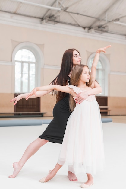 Ballerina-instructeur en meisje poising in dansstudio
