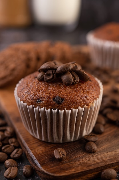 Banaan cupcakes die op een houten bord met koffiebonen worden geplaatst.