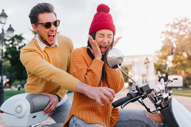 Bang dame in gebreide muts zittend op scooter met ogen dicht