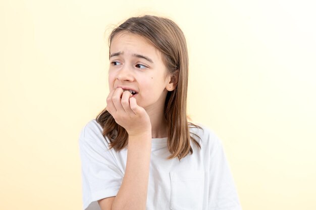 Bang en angstig meisje bijt haar nagels op een witte achtergrond geïsoleerd