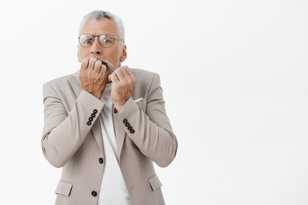 Bang en geschokt senior man vingernagels bijten en angstig op zoek