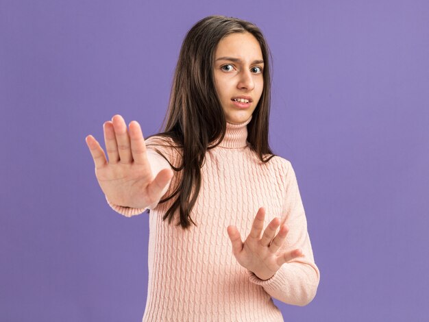 Bang mooie tienermeisje kijken camera doen weigering gebaar geïsoleerd op paarse muur met kopie ruimte
