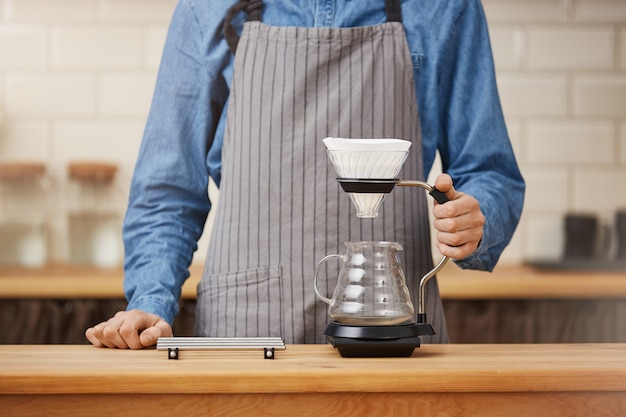 Barista bij bar over om pouron koffie te maken.