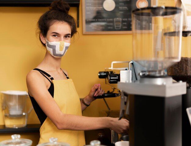 Barista die een gezichtsmasker draagt tijdens het zetten van koffie