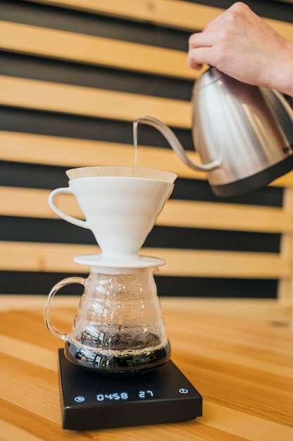 Gratis foto barista gieten heet water over koffiefilter