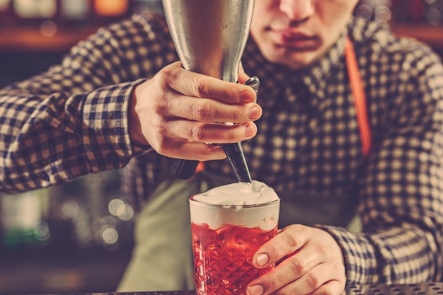 Barman die een alcoholische cocktail maakt aan de toog op de bar