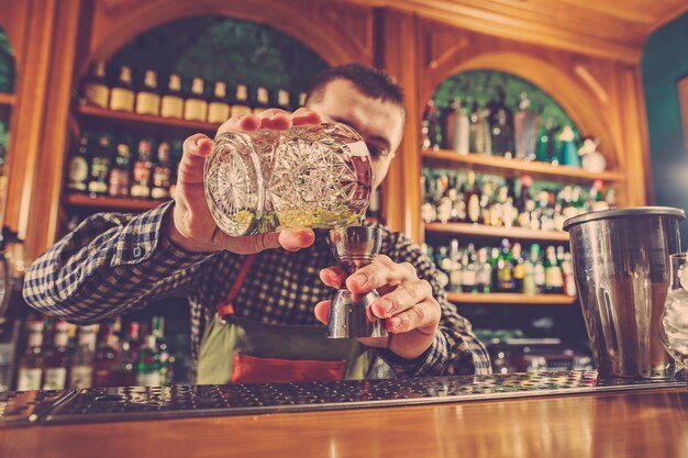 Barman die een alcoholische cocktail maakt aan de toog op de bar