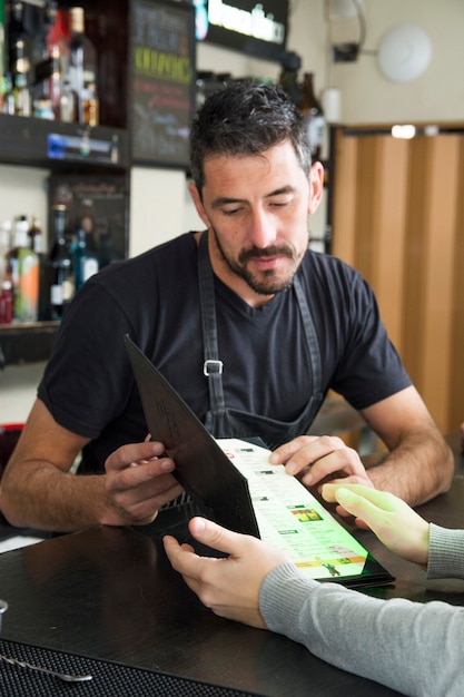 Barman die menu toont aan vrouwelijke klant bij barteller