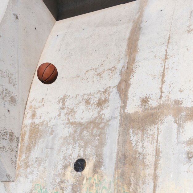 Basketbal in de lucht tegen grungemuur