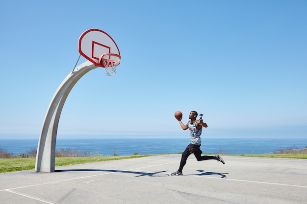 Basketbalspeler die langs de oceaan rent met selfiecamera