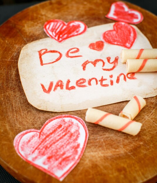 Be my valentine-berichtkaart met handgemaakte harten en aardbeienkoekjes Premium Foto