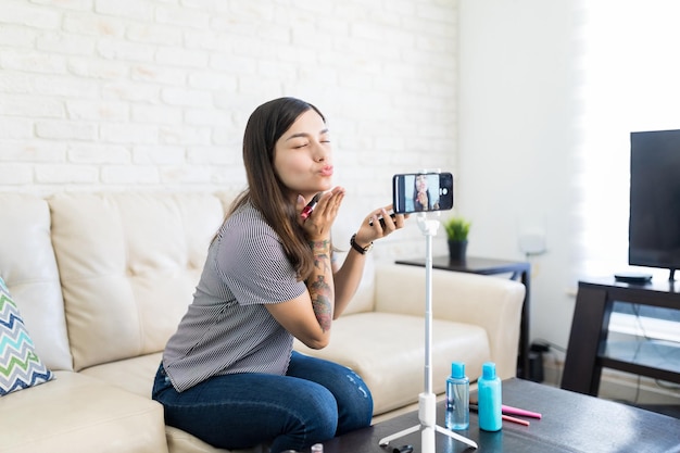 Beautyvlogger blaast kus terwijl hij online streamt via smartphone