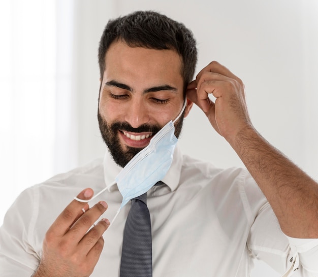 Bebaarde arts die zijn medisch masker opstijgt