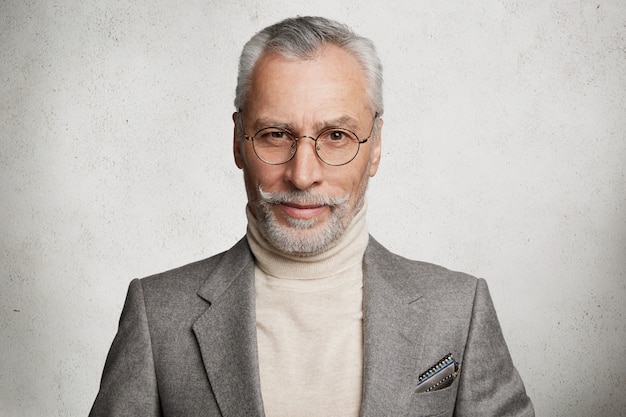 Gratis foto bebaarde grijsharige oudere man gekleed in formeel pak