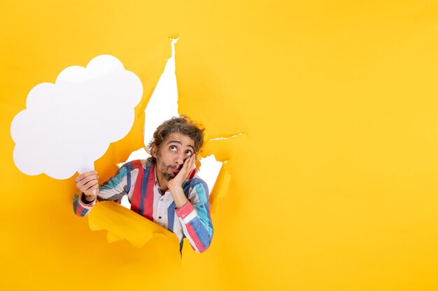 Bebaarde man die wit wolkvormig papier vasthoudt en diep nadenkt in een gescheurd gat en een vrije achtergrond in geel papier