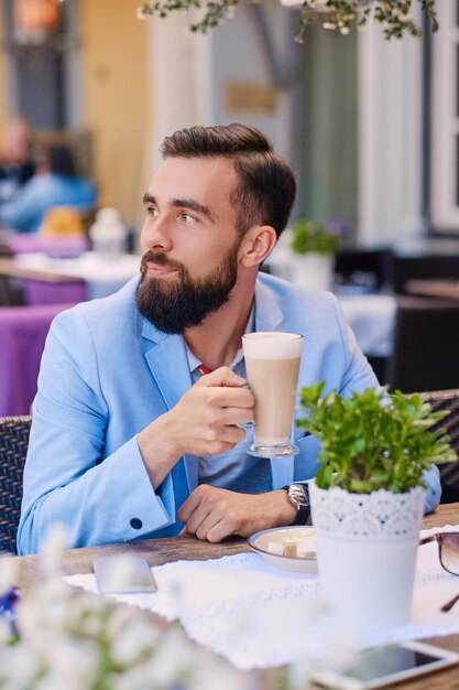 Bebaarde man drinkt koffie in een café.