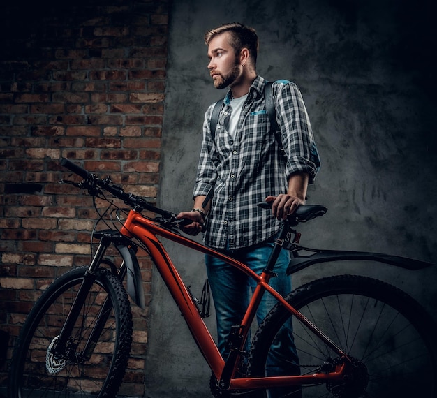 Bebaarde man gekleed in een fleece shirt houdt rode mountainbike vast.