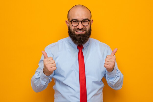 Bebaarde man in rode stropdas en blauw shirt met een bril die er blij en opgewonden uitziet met duimen omhoog
