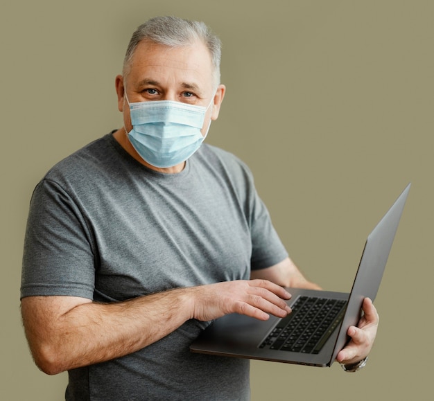 Gratis foto bebaarde man met chirurgisch masker met laptop