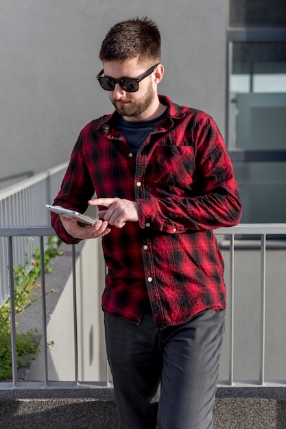 Gratis foto bebaarde man met een zonnebril met behulp van tablet pc