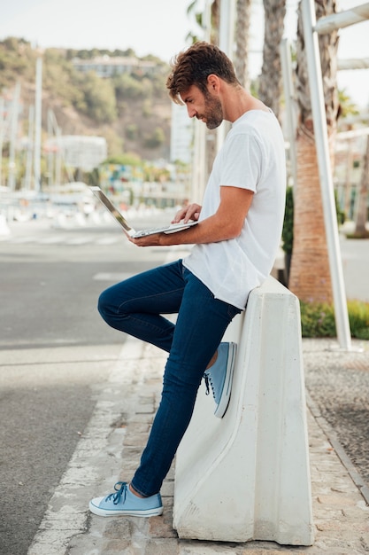 Bebaarde man met jeans met een laptop