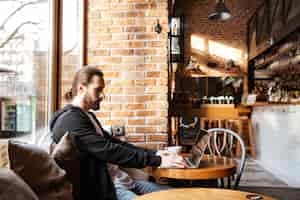 Gratis foto bebaarde man met laptop in café