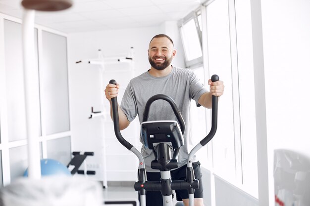 Bebaarde man met spin-fiets in fysiotherapie kamer