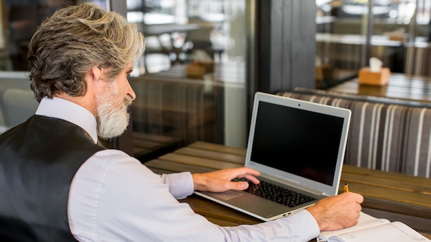 Gratis foto bebaarde senior man aan het werk op laptop