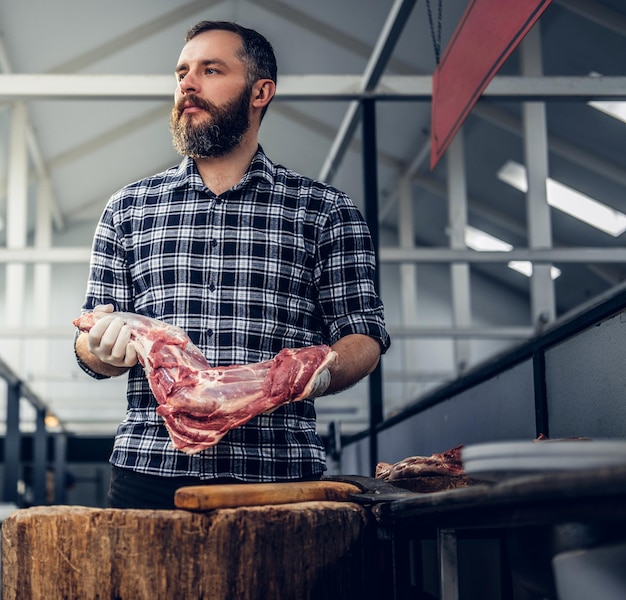 Bebaarde slager gekleed in een fleece shirt aan het werk in slagerij