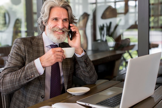 Gratis foto bebaarde volwassen man genieten van koffie op kantoor