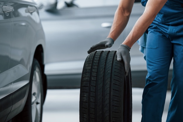 Bedrijf van autoreparatie. Monteur met een band bij de reparatiegarage. Vervanging van winter- en zomerbanden