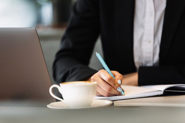 Bedrijfs vrouw die laptop computer het schrijven nota's met behulp van