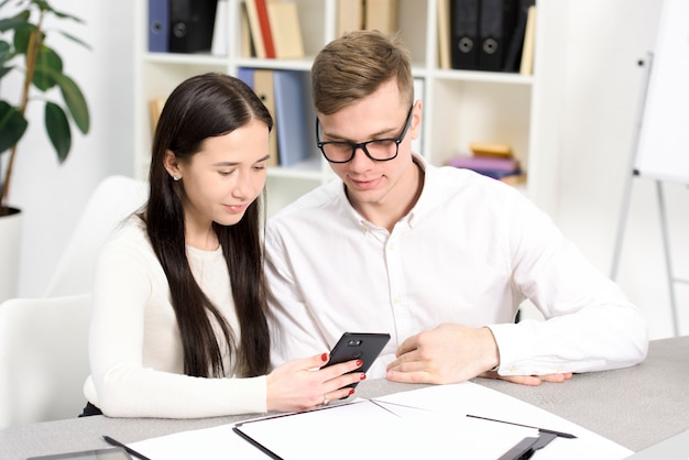 Bedrijfscollega&#39;s die cellphone op het werk in het bureau bekijken