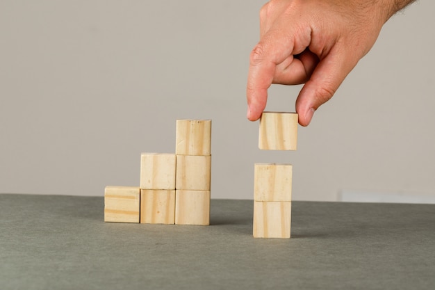 Bedrijfsgroei concept op grijs en wit muur zijaanzicht. man schikken hout blok stapelen trap.