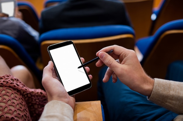 Bedrijfsleiders die deelnemen aan een zakelijke bijeenkomst met behulp van mobiele telefoon