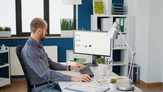 Bedrijfsmedewerker die werkt met verkoopstatistieken op grafieken, met behulp van gegevens op de computer om bedrijfsgroei te creëren. Beambte die financieel onderzoek plant met diagrammen voor ontwikkeling.