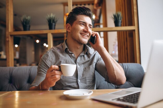 Bedrijfsmens in een koffie die op de telefoon en het drinken koffie spreken