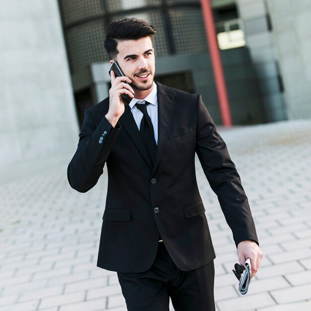 Bedrijfsmens voor het bureaugebouw die zijn mobiele telefoon gebruiken